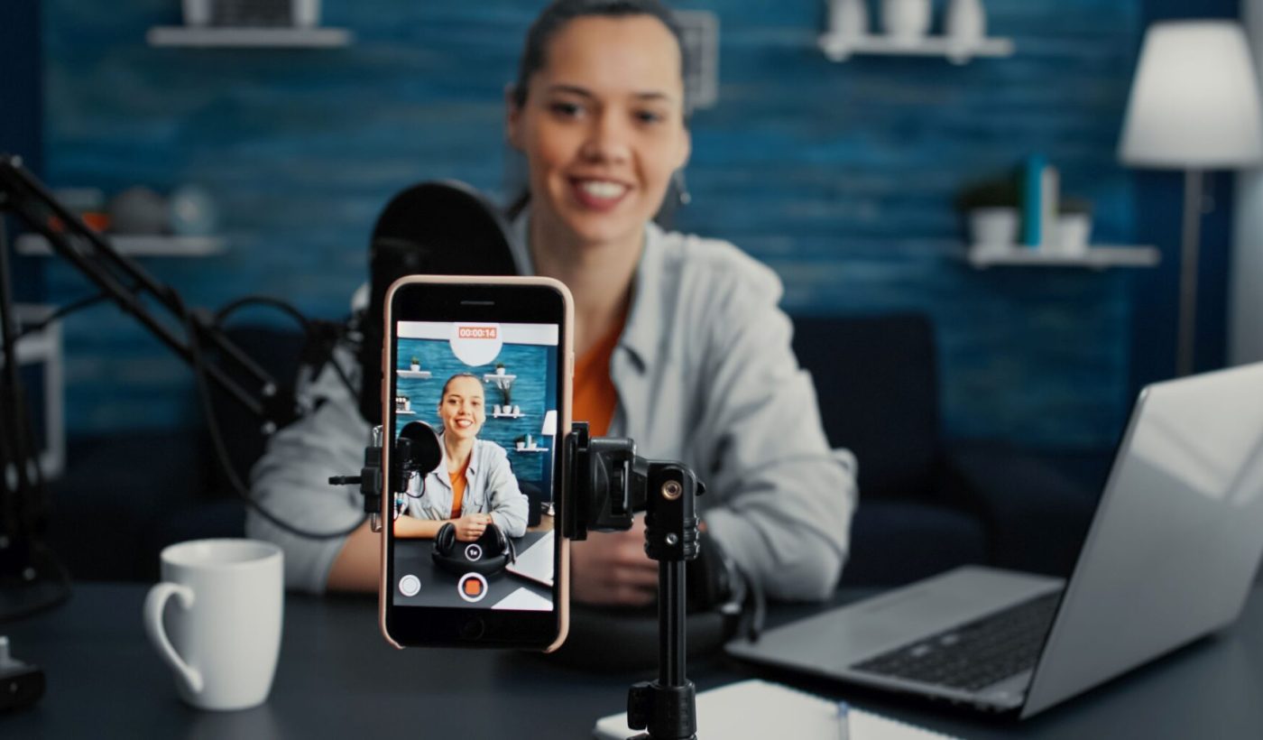 Attractive social media influencer sitting at home studio desk while starting streaming